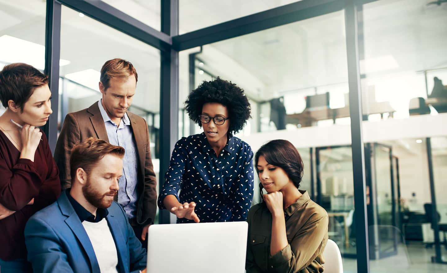 A group of professionals in an office looking at a computer screen.