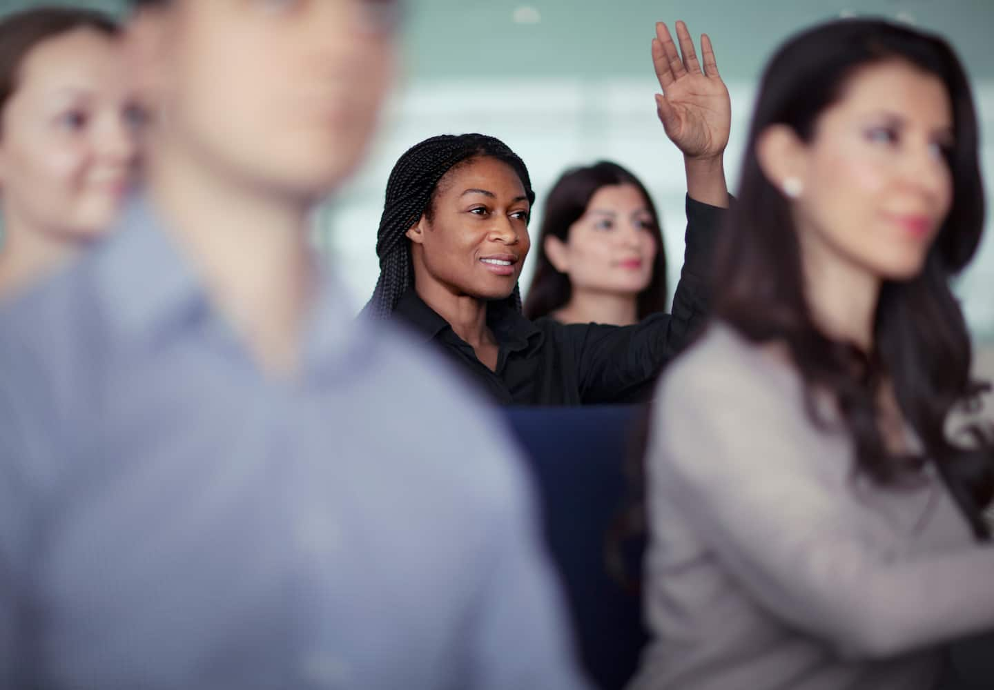 Woman raising her hand amongst colleagues.