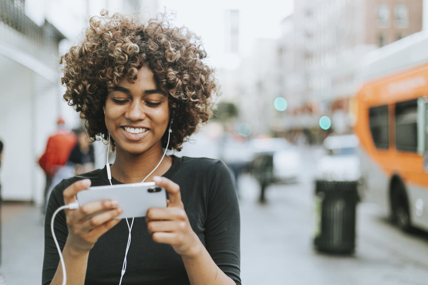 Girl wearing headphones looking at her phone's screen